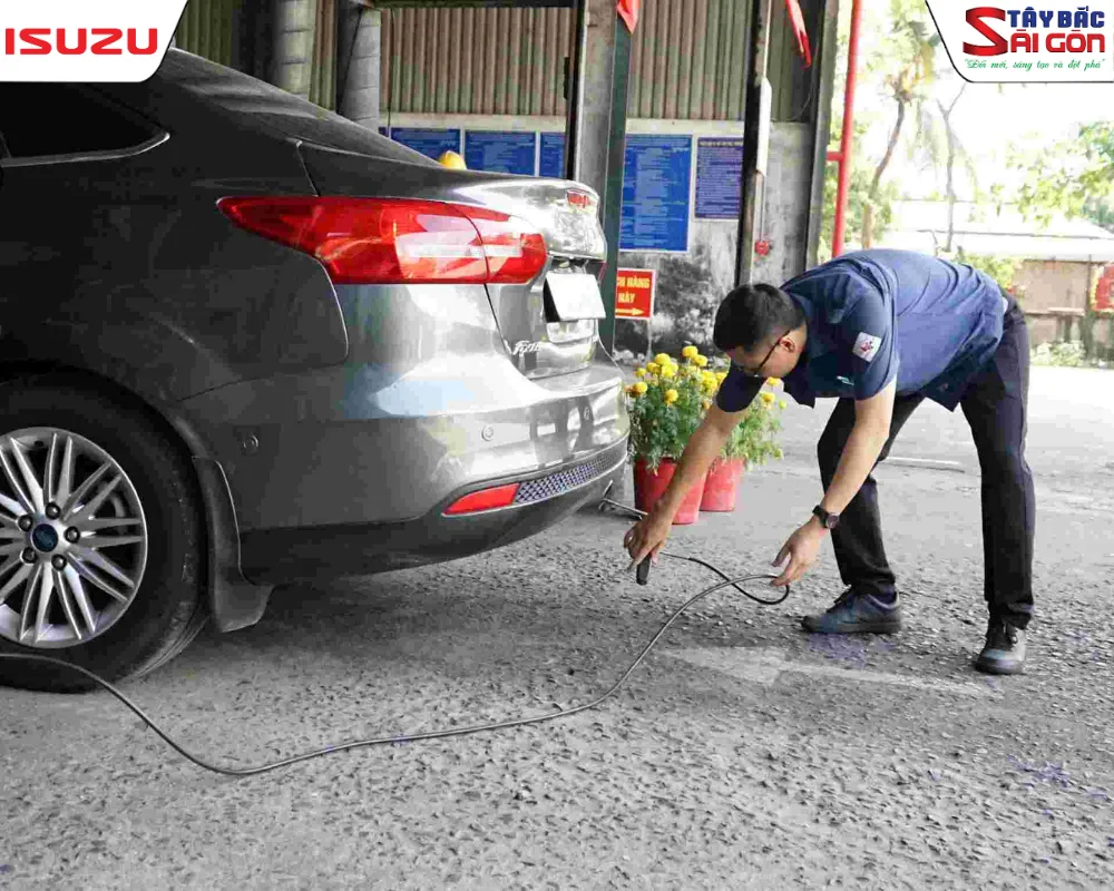 Kỹ thuật viên trạm kiểm định đang cắm ống đo vào bô xe tải để kiểm tra đăng kiểm khí thải.