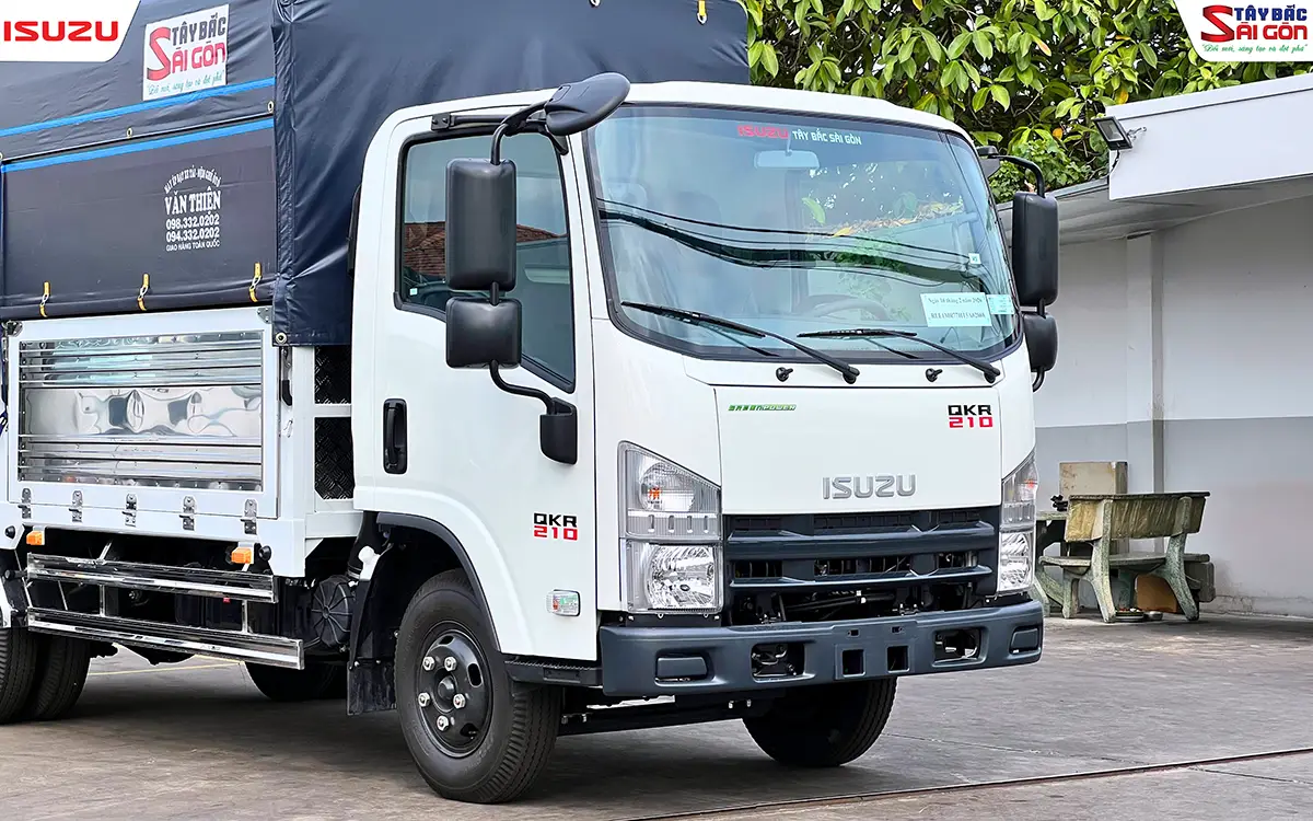 Đầu xe nhìn gần, cabin trắng có bậc lên xuống và bửng hông kim loại sáng phía sau cửa