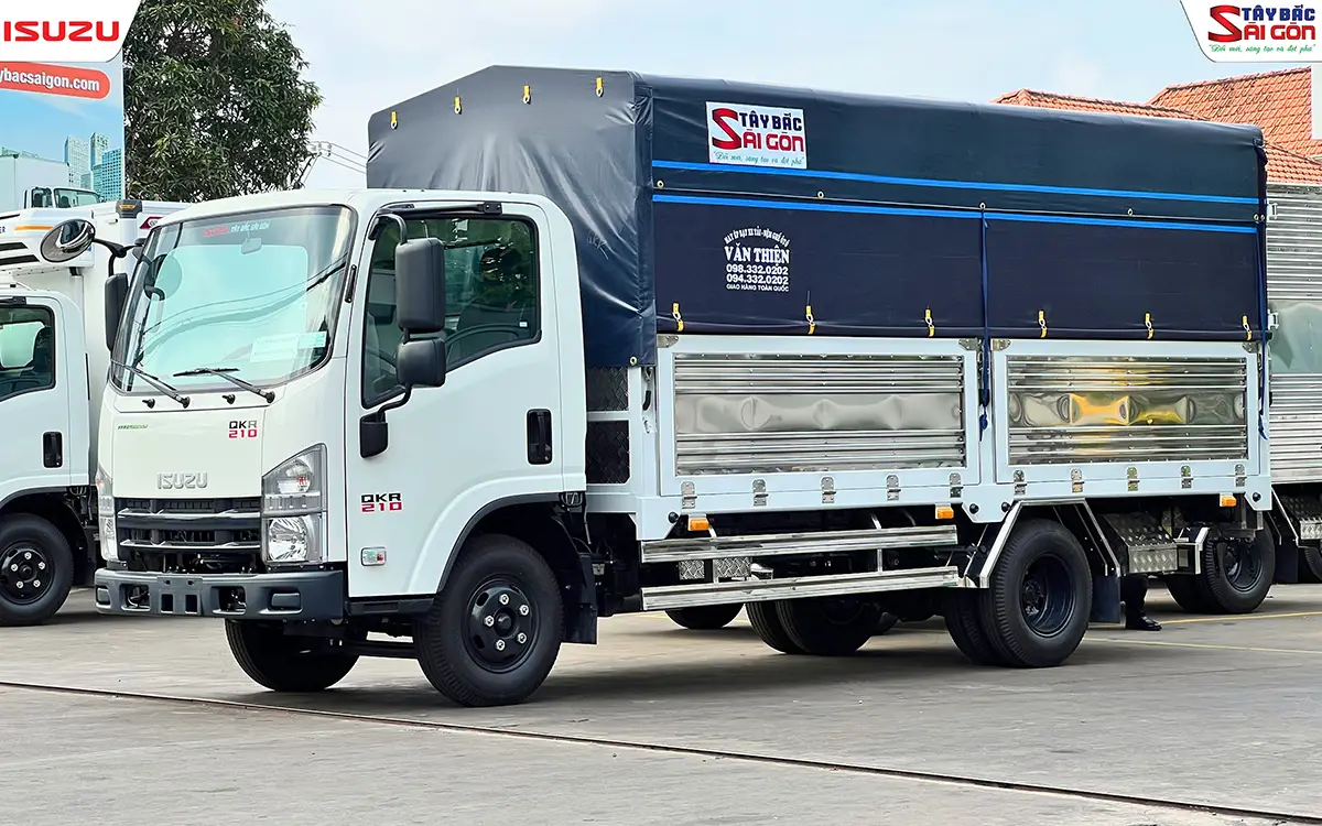 Hông thùng mui bạt với hai ô bửng kim loại sáng, nhìn chéo từ phía trước cabin